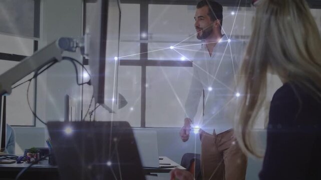 Standing man reviewing business monitor, celebrating with peer by high five as network overlay