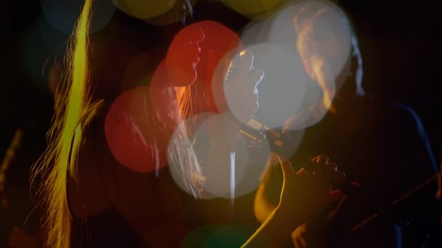 Vocalist and guitarist performing duet for recording, bokeh discs shifting to reveal profiles