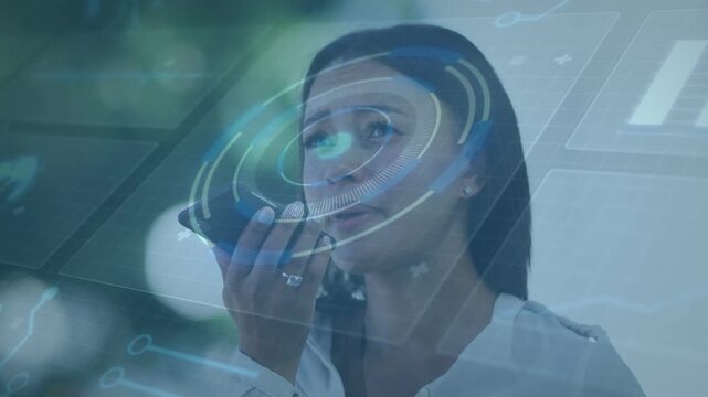 Woman lifting smartphone near mouth dictating tech note while rotating holographic circle pulsing