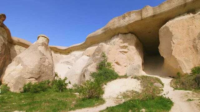A wide shot of the surreal and unique landscape of the Cappadocia region in Central Anatolia, Turkey. The image features several "fairy chimney" rock formations, which are tall, naturally occurring co