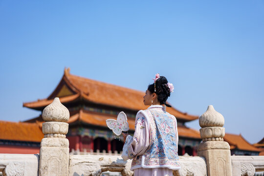 Happy Asian woman in traditional Chinese dress enjoying at Forbidden City in Beijing, China