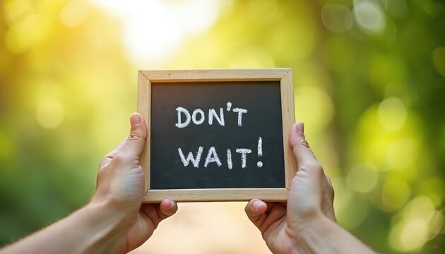 Person holds small blackboard with text Dont Wait. Message against blurred green trees. Natural background conveys urgency action positive attitude. Take initiative now.
