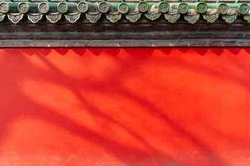 Fototapete Rot Shadows of Tree Branches Silhouetted Against a Vibrant Red Traditional Chinese Palace Wall in Bright Sunlight, Background and textured  © Kittiphan