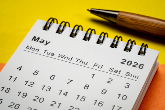May 2026 - small spiral desktop calendar against art paper abstract, time and business concept