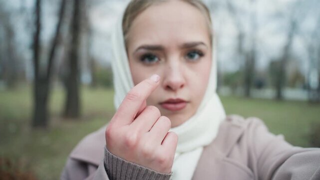 Young woman in scarf pleading with camera, emotional plea and determined gaze in frosty park, closeup hands reaching forward with raw vulnerability, winter trees and muted tones create cinematic mood