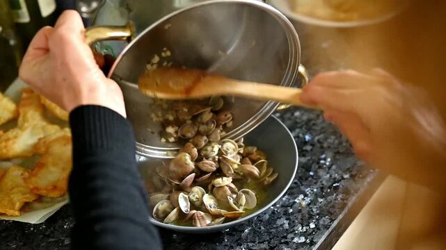 Serving garlic clams with white wine sauce from pan into a plate homemade Mediterranean food ready to eat family meal, seafood concept, healthy food