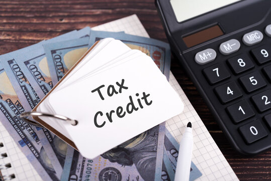 Memo pad with text Tax Credit on top of US dollars and calculator