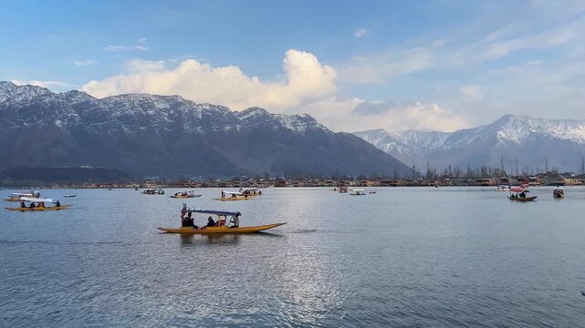 Shikara boats with tourists sailing on beautiful Dal Lake with snow mountains in Srinagar Kashmir