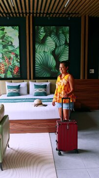 Cheerful female traveler arriving in a tropical hotel room