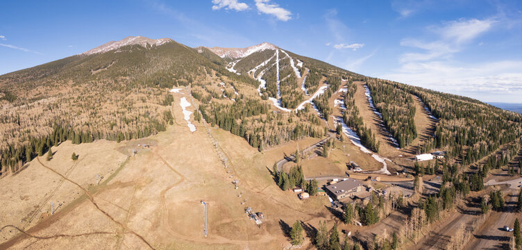 Panoramic view of Arizona snowbowl ski resort near Flagstaff, USA, suffering from unusual lack of snow in early april 2026, due to climate change. Aerial view, late afternoon.