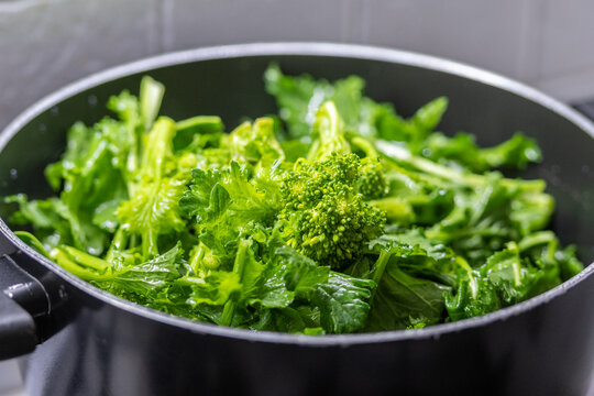 Washing cime di rapa, turnip greens, rapini or broccoli rabe in a bowl