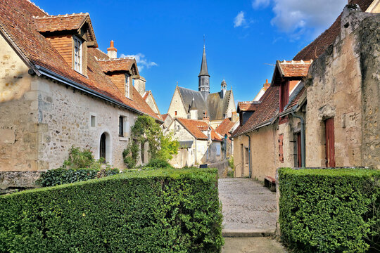 Beautiful streets of Montresor in the Loire Valley of France. Picturesque stone houses, leafy vines and church in the background.