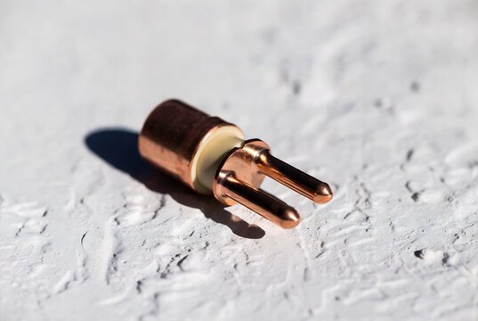A copper electrical contact is resting on textured concrete.