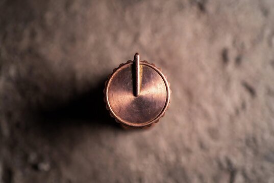 A copper potentiometer knob rests on textured concrete.