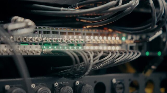 Video of Rack-Mounted Patch Panel with Dense Cable Wiring and Glowing LED Indicators &mdash; Broadcast or Event Technical Infrastructure in Dark Studio Environment