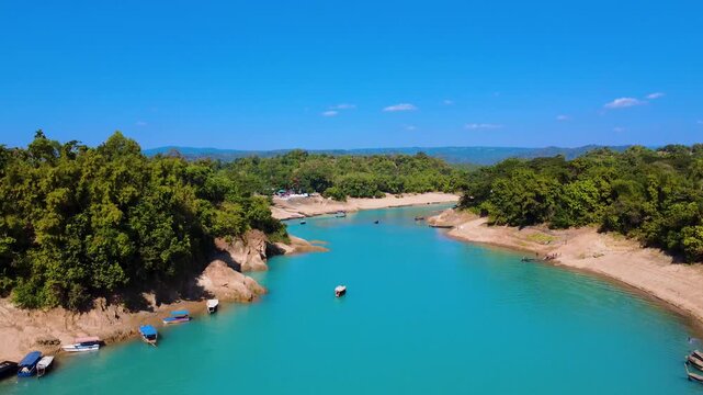 A scenic drone view of the Lalakhal Sari-Goain River in Jaintapur, Sylhet, slowly descending from above, under clear blue skies, which is known as a famous tourist destination in Bangladesh.