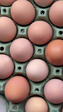 A close-up shot of fresh eggs. Fresh farm eggs of various sizes are stacked in a cardboard box.