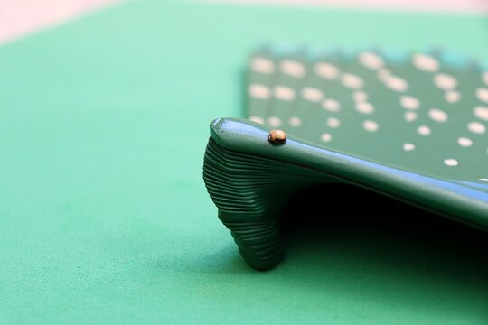 Close-up of a green hand fan with white polka dots against a matching green background. 