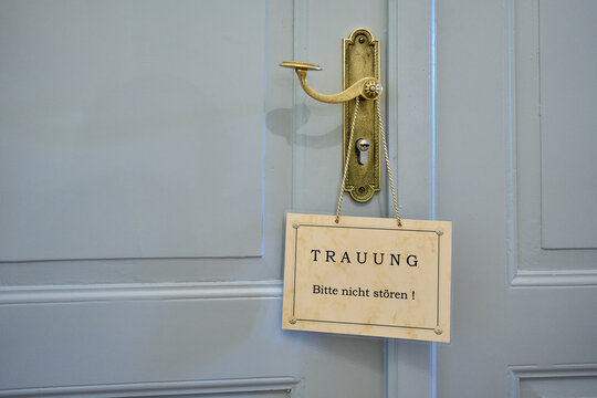 A vintage door handle with a German sign "Trauung - Bitte nicht st&ouml;ren!" (Wedding - Please do not disturb). Concept of private marriage ceremony.