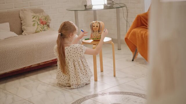 Child examines pumpkin. Girl with braided hair inspects jar. Young girl sits peacefully by pumpkin decor. Girl wearing polkadot attire comfortably studies pumpkin jar in cozy autumn setting