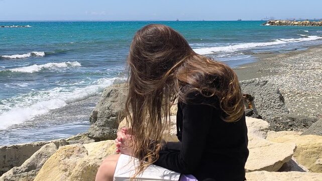 Young Christian Teen Girl Praying with Bible by the Rocky Seashore - Slow Motion Half Speed
