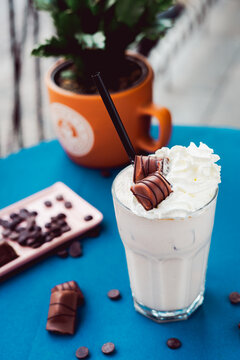 Smoothie with a creamy flavor in a glass on a wooden table, decorated with  chocolate wafer, healthy summer drink, vibrant colors, natural light.