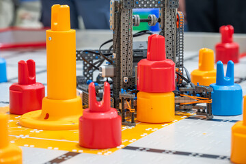 Fototapeta premium Robots and colorful game pieces are set on a table during a competition in a school hall in the afternoon