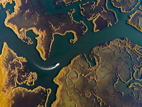 Aerial view of Dalyan River Delta with boats moving through winding channels and wetlands. Natural patterns, marsh ecosystem, tourism activity, water landscape and environmental conservation concept. 