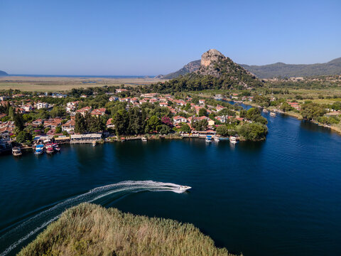 Aerial view of Dalyan town and river with boats moving on water. Coastal settlement, summer tourism, waterfront lifestyle, scenic landscape and travel destination concept. Ortaca, Mugla