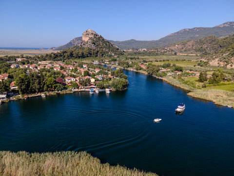 Aerial view of Dalyan town and river with boats moving on water. Coastal settlement, summer tourism, waterfront lifestyle, scenic landscape and travel destination concept. Ortaca, Mugla
