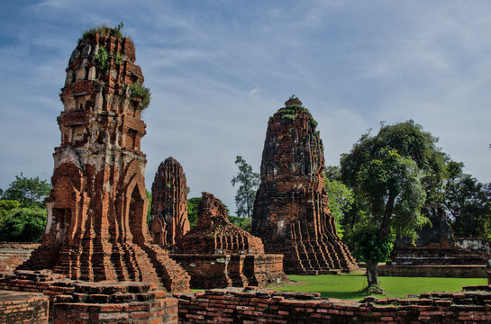 Ancient stone multi-faced or three-headed Buddha statue among ruins at Ayutthaya Historical Park, Thailand, showing detailed carved features.