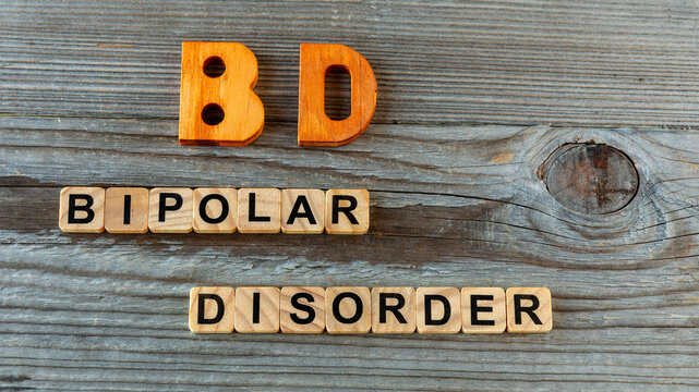 BD abbreviation on wooden letters and its individual words: Bipolar Disorder, spelled out with wooden letter tiles on aged wooden boards.
