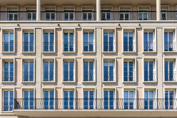 Fototapeta premium Detail of the facade of a post war concrete apartment building with rows of large windows on a sunny summer day