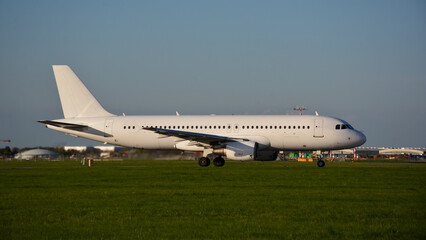 Obraz premium Airbus A320-200 in an all white and blank livery during sunset on green gras