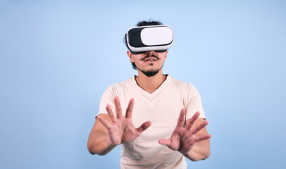 Naklejka premium latin man using virtual reality glasses on blue background in Mexico Latin America, or mexican young adult male portrait