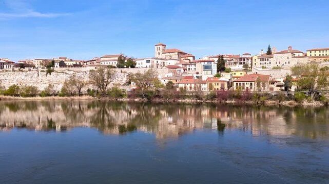 A sweeping horizontal panorama from the Stone Bridge reveals Zamora Cathedral rising over the historic old town, with the Duero River flowing steadily alongside the city. Zamora, Spain