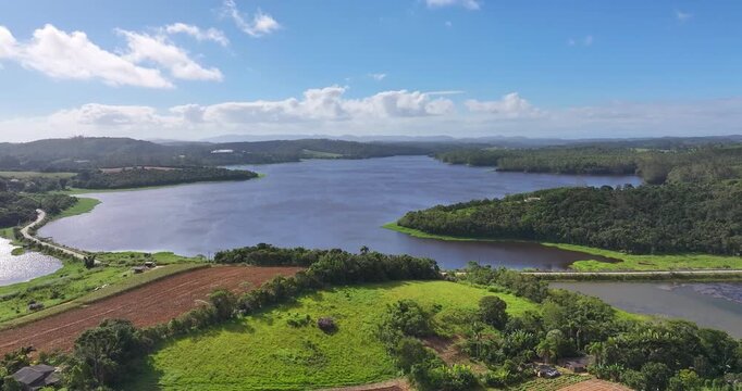 4K aerial drone view of Alto Tiete reservoir in Brazil, showing water storage, rural landscape, forests and agricultural fields under blue sky