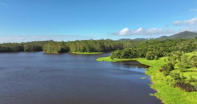 4K aerial drone view of Alto Tiete reservoir in Brazil, showing water storage, rural landscape, forests and agricultural fields under blue sky