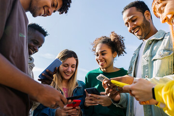 Naklejka na ściany i meble Young group of teenage student friends using smart phones outdoors. Youth and technology lifestyle concept