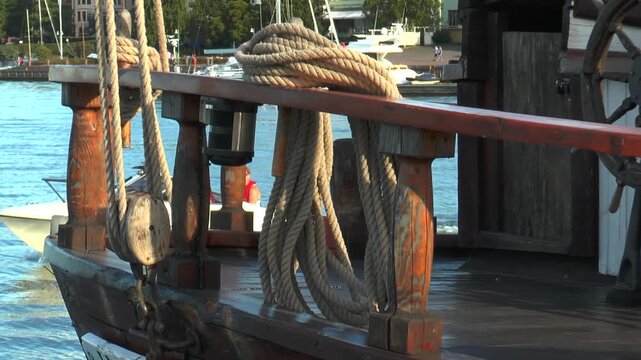 HELSINKI, FINLAND - August 6, 2013: an Old sailing schooner at the pier is rocking on the waves. Equipment schooner - wooden blocks, ropes, fencing, steering wheel.
On warm summer evening.