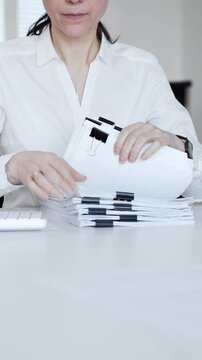 Businesswoman hands organizing stack of papers with binder clips, working on financial documents and official reports in office. Audit and taxes concept
