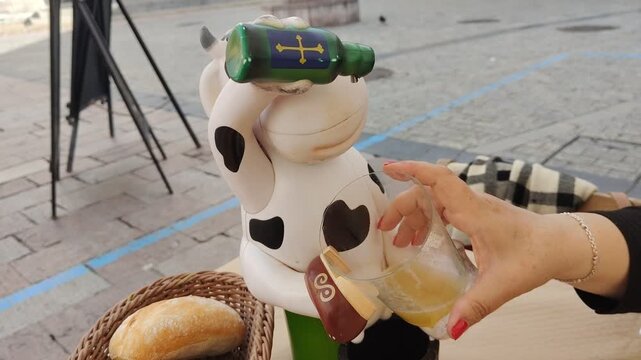 Woman pouring typical asturian cider at an outdoor cafe