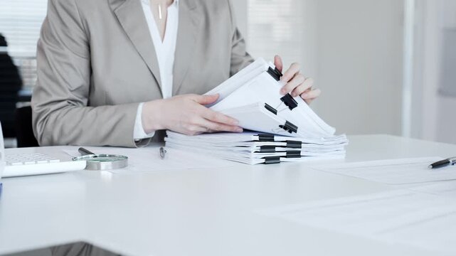 Businesswoman hands organizing stack of papers with binder clips, working on financial documents and official reports in office. Audit and taxes concept