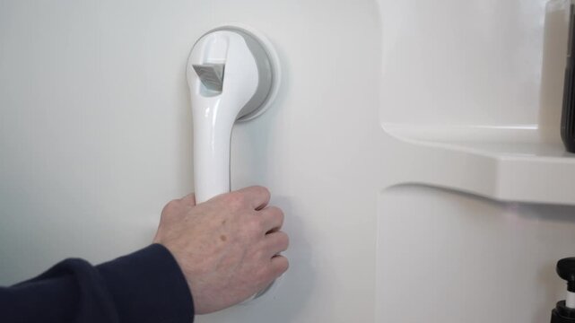 Removing a suction cup grab handle from inside a stand-up shower stall. Home safety and senior assistance concept. 15113  