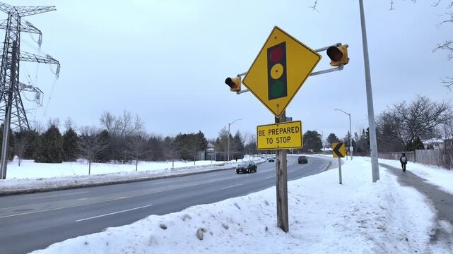 Winter road traffic with a flashing traffic light warning sign in Toronto