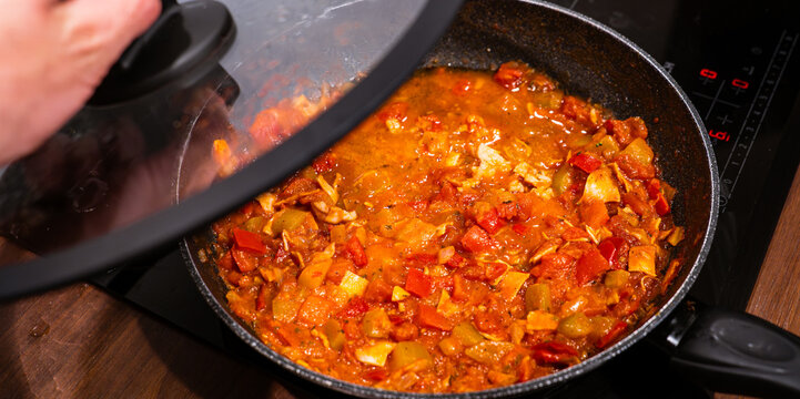 Homemade vegetable stew with peppers and tomatoes under a glass lid