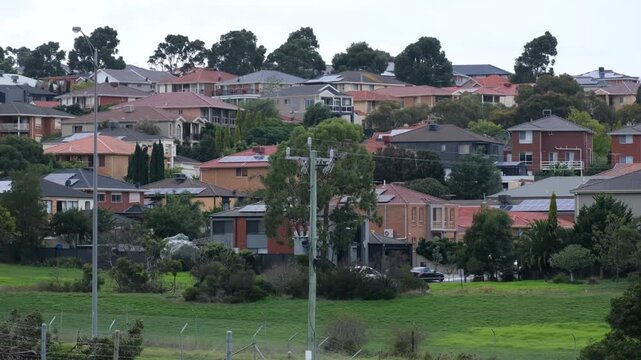 Roxburgh Park suburban hillside neighbourhood with dense residential housing and green open space in Melbourne, Australia. Car traffic flowing along streets near homes in a northern suburb.