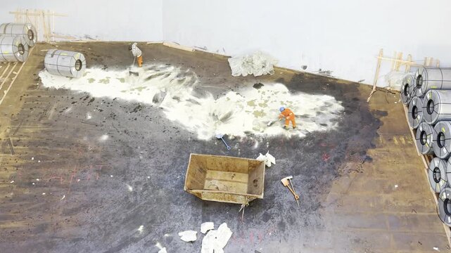 stevedores inside the ships cargo hold remove the oil spillage caused by heavy machine during discharging cargo