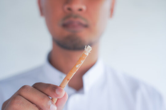 Man holding miswak for traditional oral hygiene