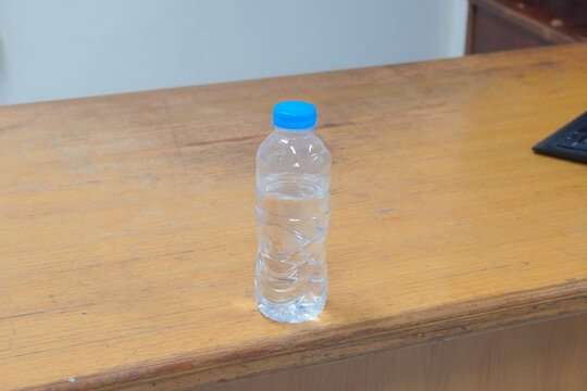 A clear plastic bottle of water sits on a wooden table